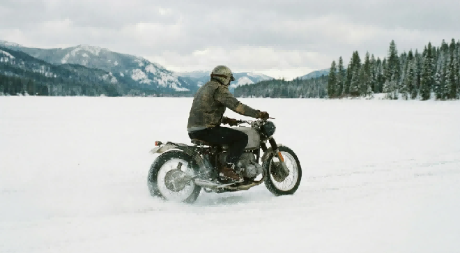 Motorcyclist riding across a snowy landscape